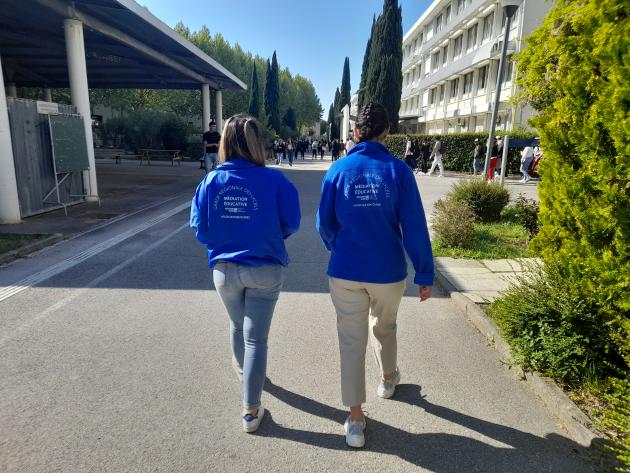 Deux médiatrices de dos aux abords d'un lycée