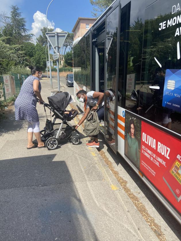 Un médiateur aide à monter la poussette d'un bébé dans un bus